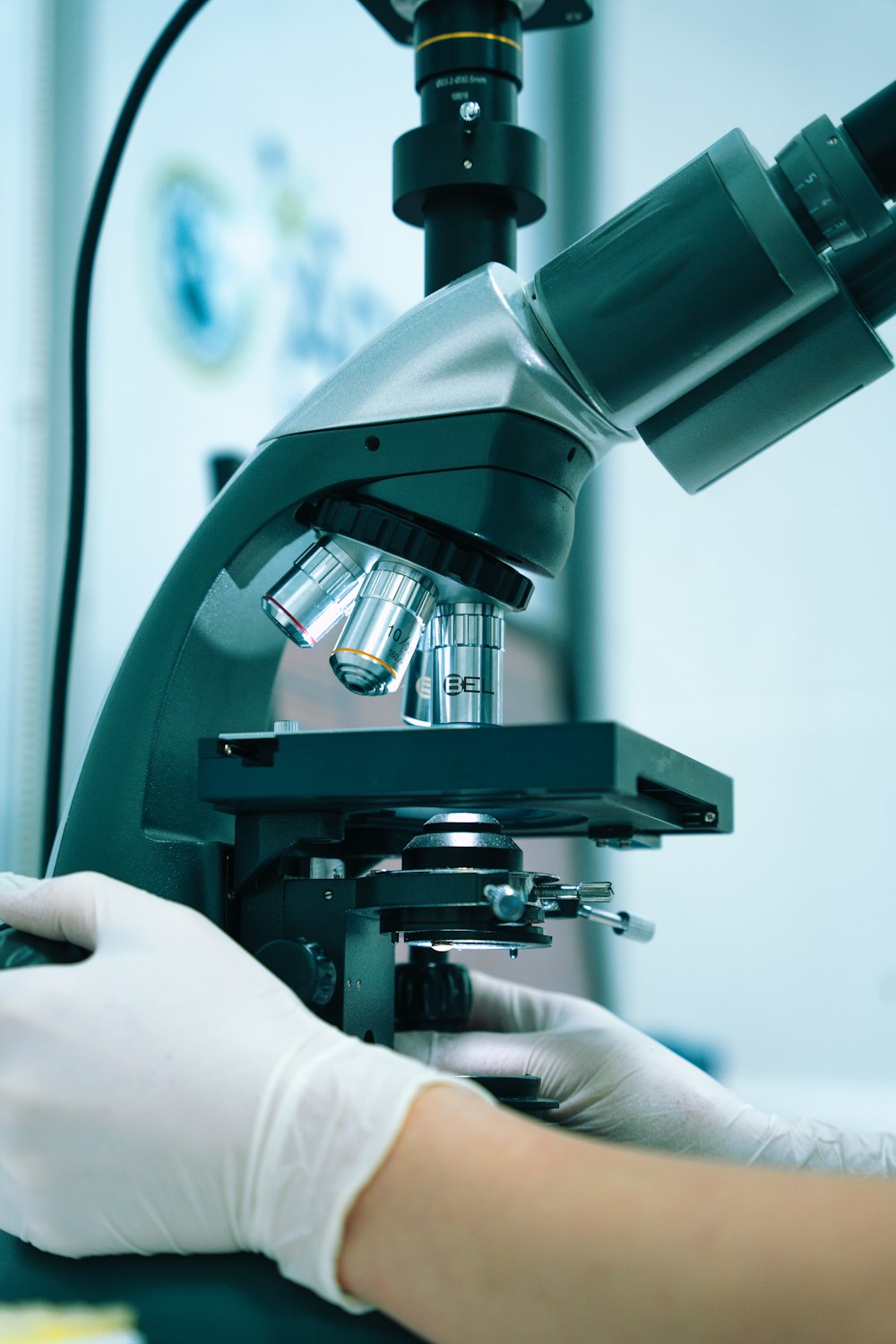 Una mano enguantada operando un microscopio en un laboratorio