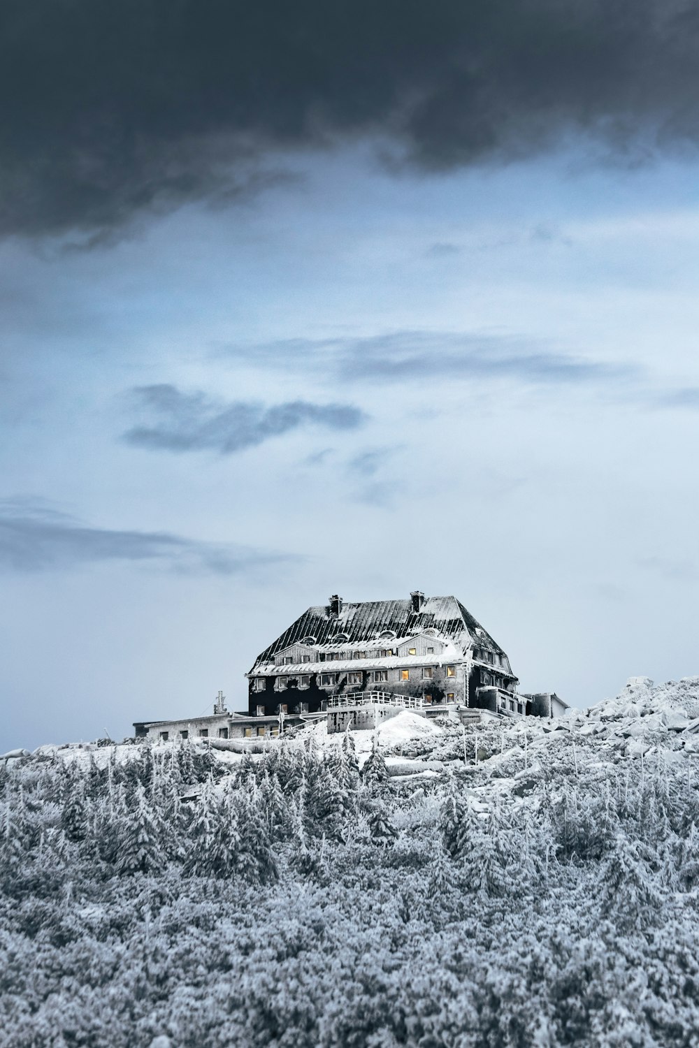 Una casa seduta sulla cima di una collina coperta di neve