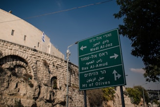 a street sign in front of a stone wall