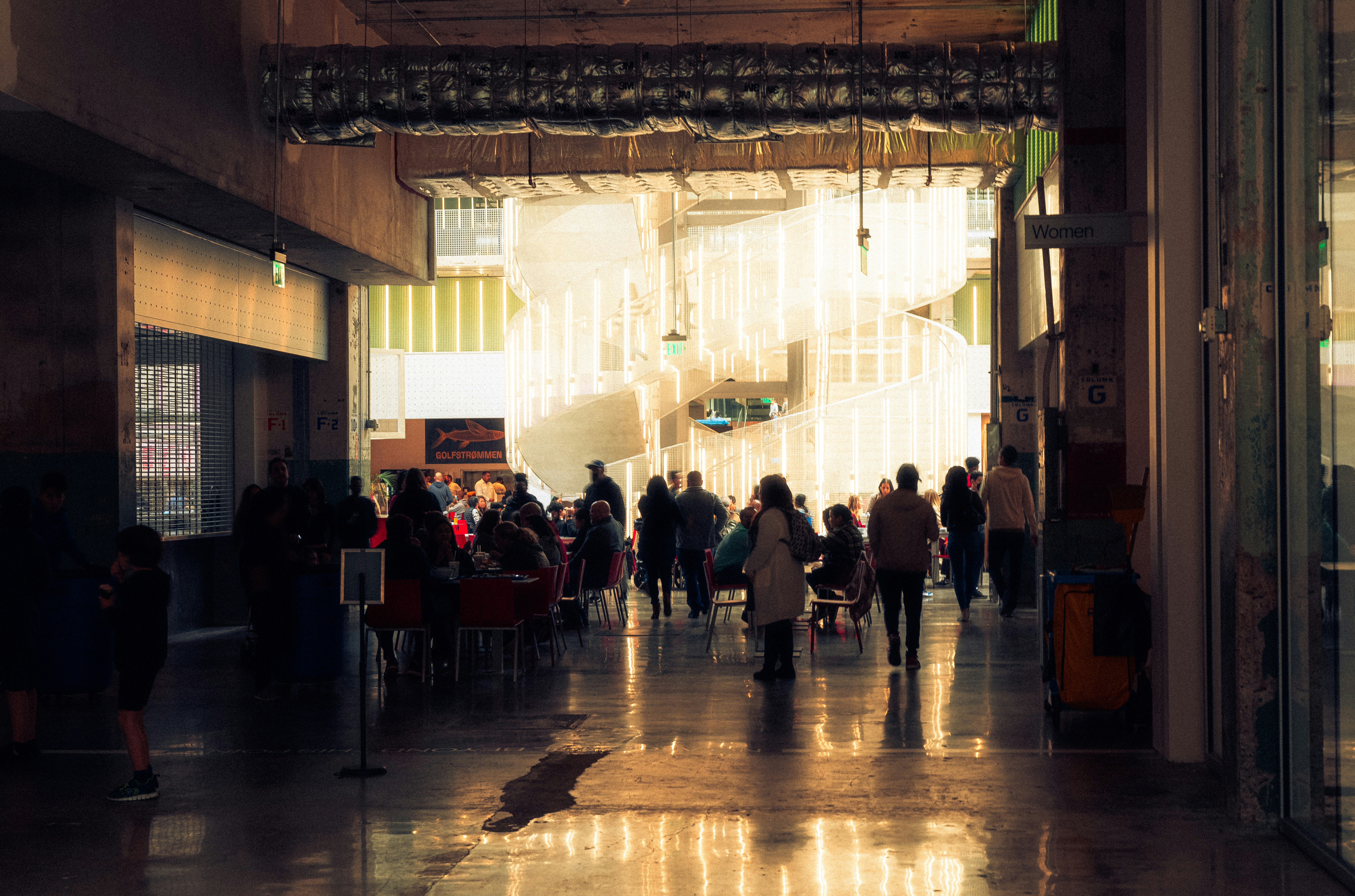 a group of people walking down a hallway, the food hall of POST Houston, an old post office given new life. 