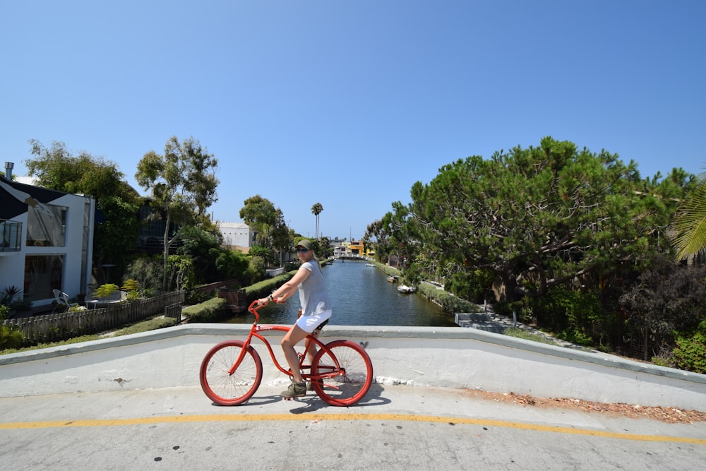 a man riding a red bike down a street next to a river