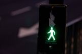a green pedestrian walk sign on a pole