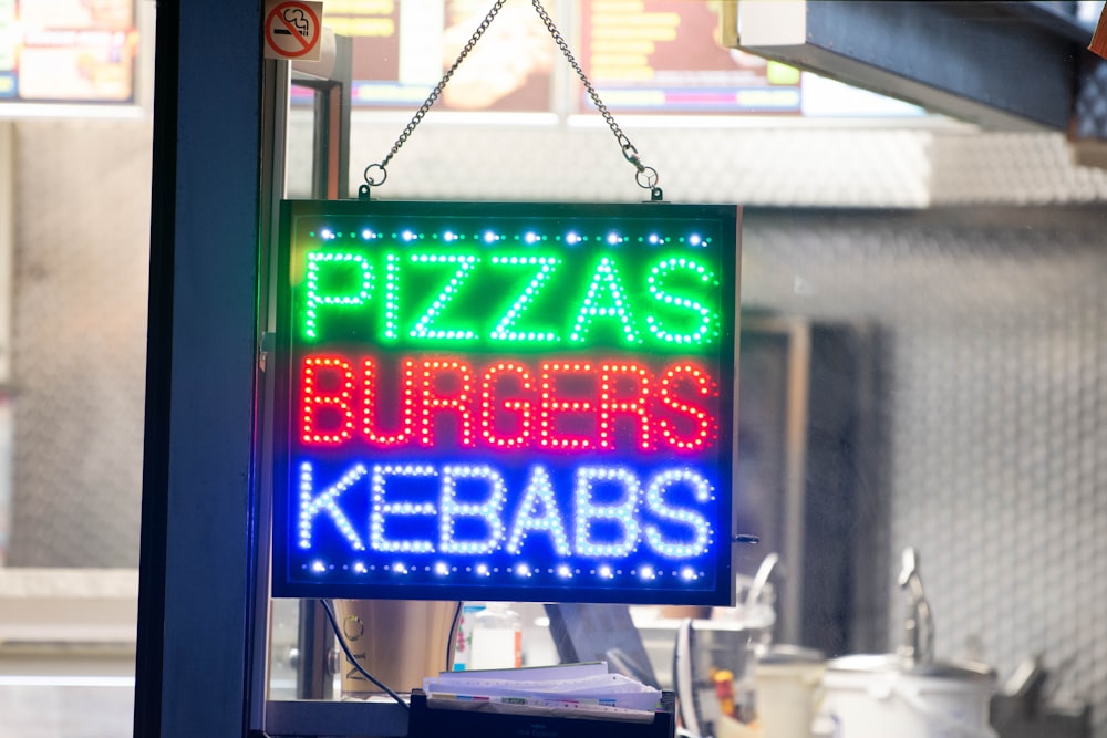 a neon sign that says pizzas, burgers, kebabs