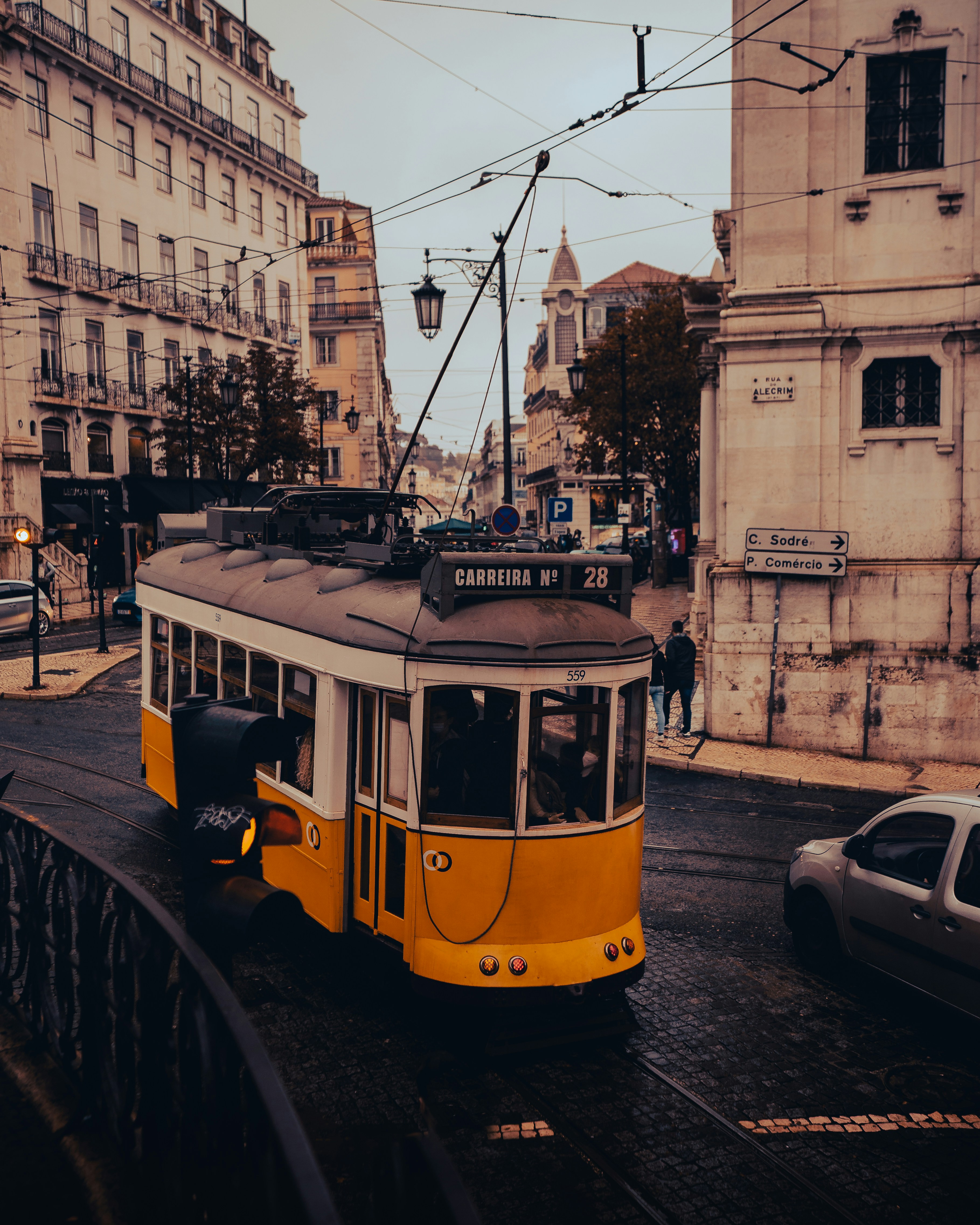 a yellow trolley car traveling down a street next to tall buildings