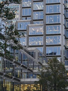 Modern corporate office building with geometric design elements and subtle animated lines in the background.