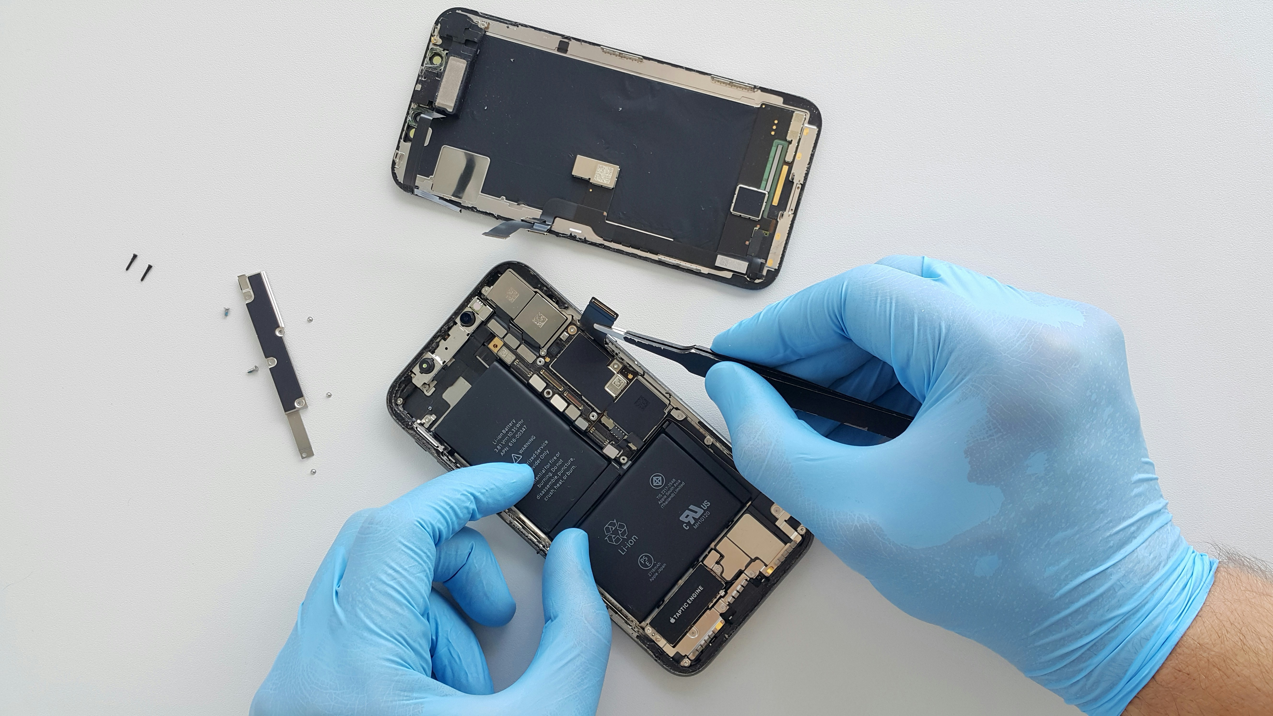 a person in blue gloves is repairing a cell phone