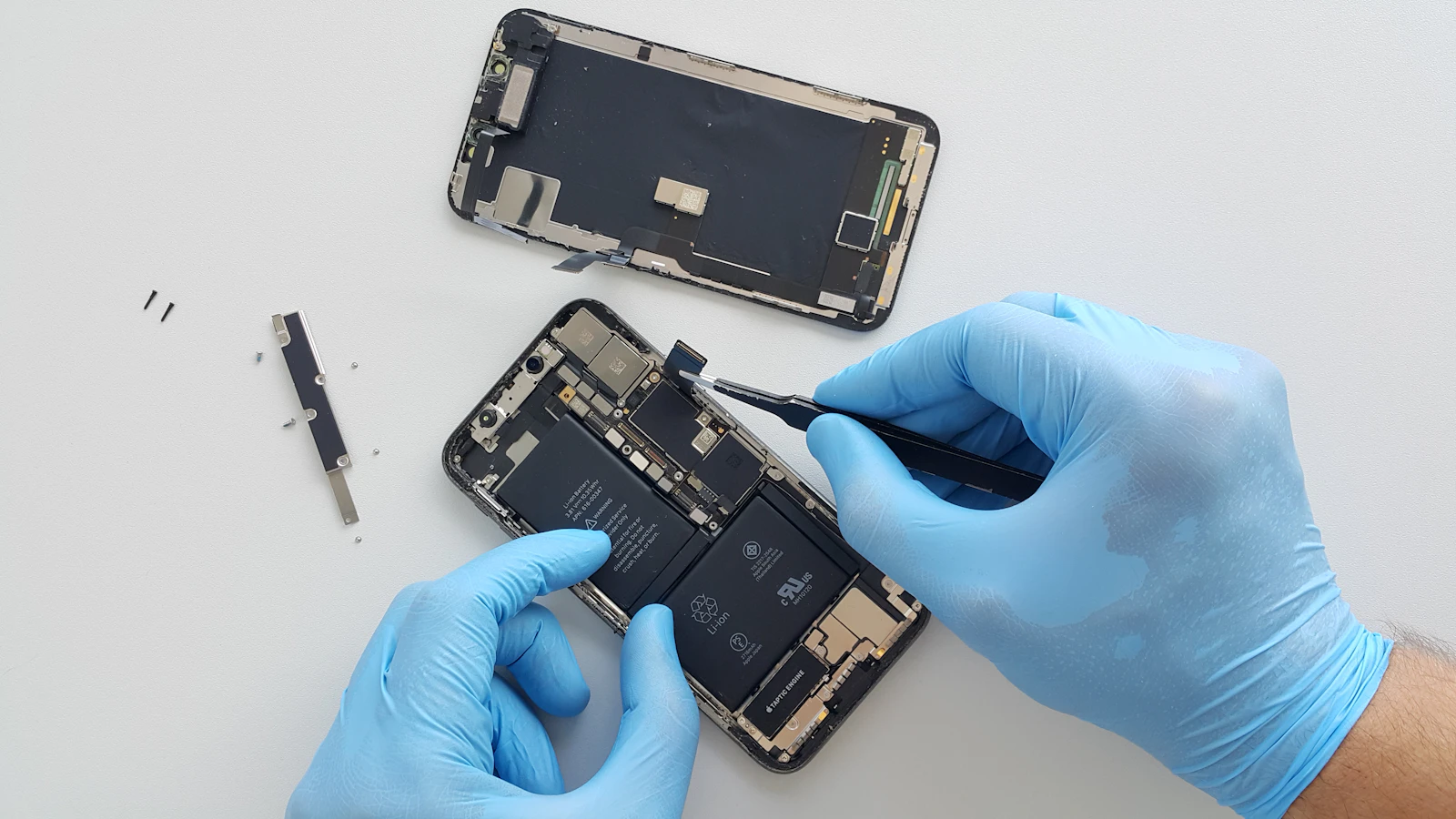A technician in blue gloves repairing the inside of a mobile phone