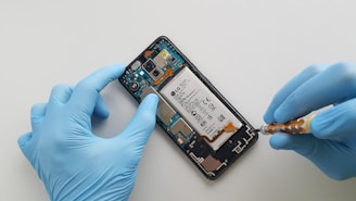 a person in blue gloves is removing a cell phone