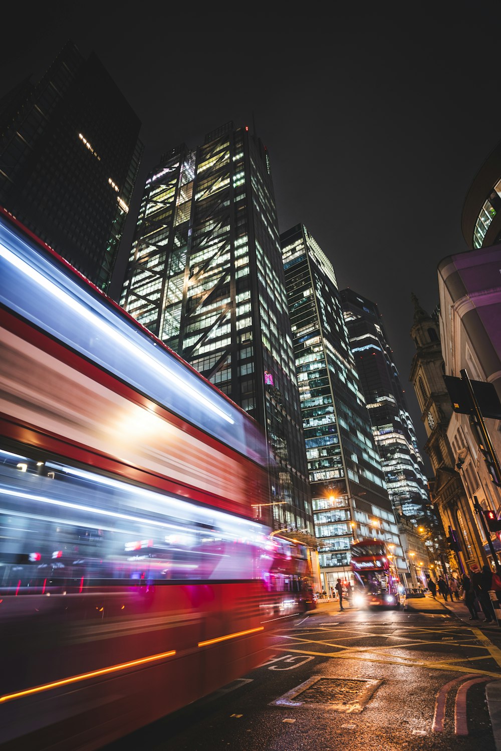 a double decker bus driving down a city street at night