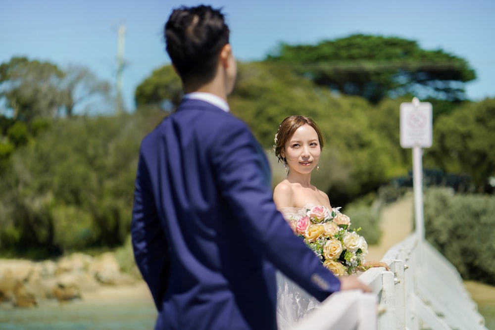 a bride and groom standing on a bridge