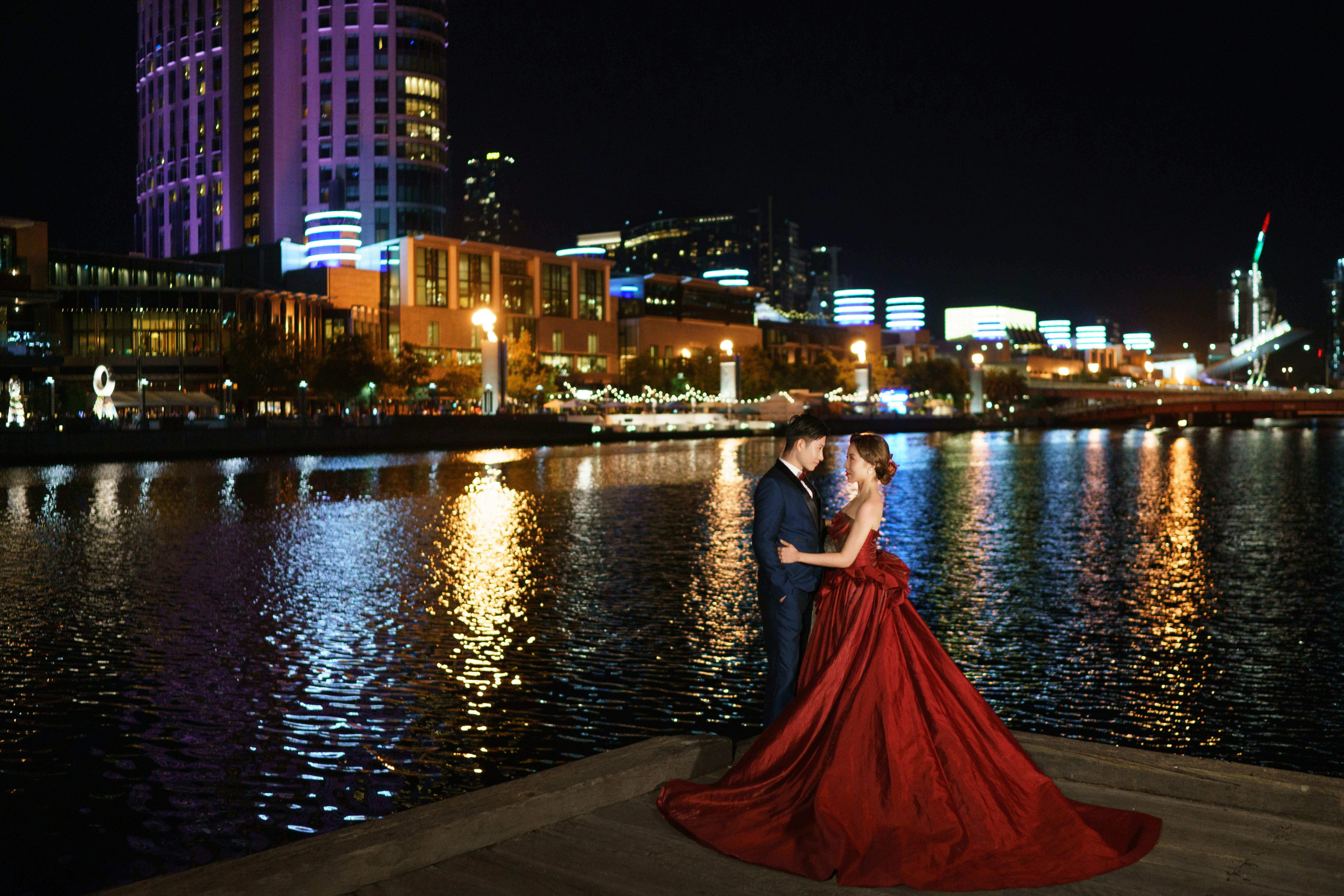 a man and a woman standing on a dock in front of a body of water