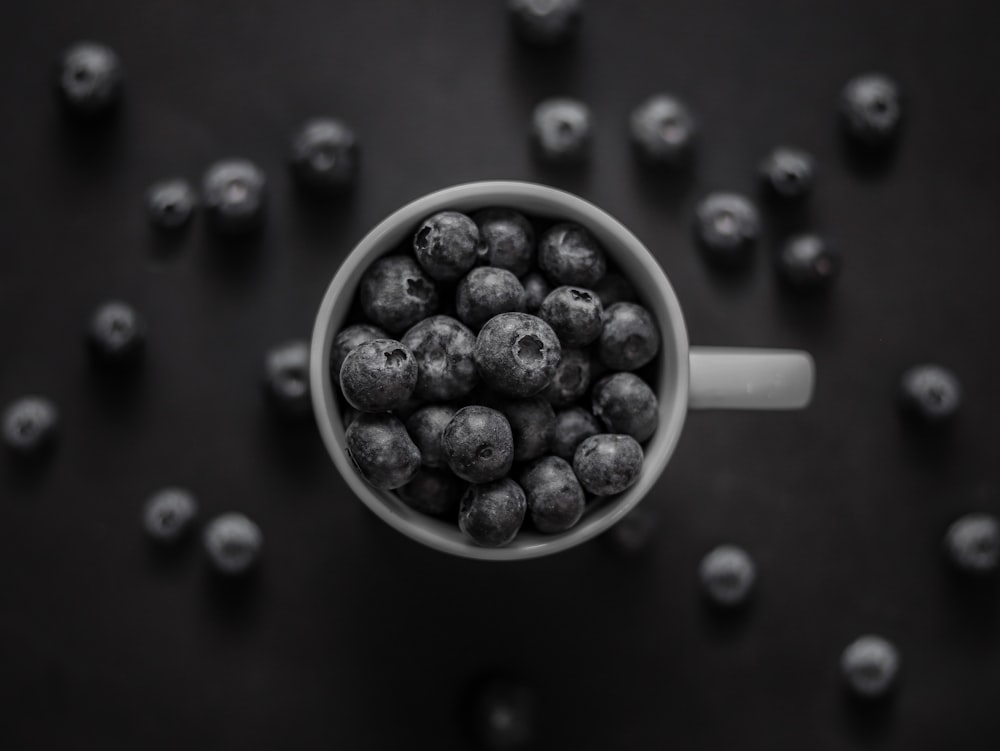 a cup filled with blueberries sitting on top of a table