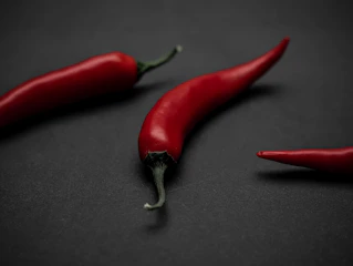 Scattered red chili peppers on a dark textured background.