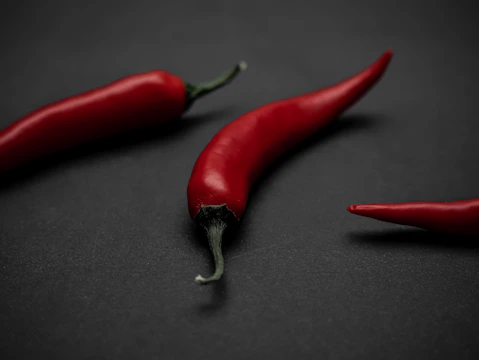 Scattered red chili peppers on a dark textured background.