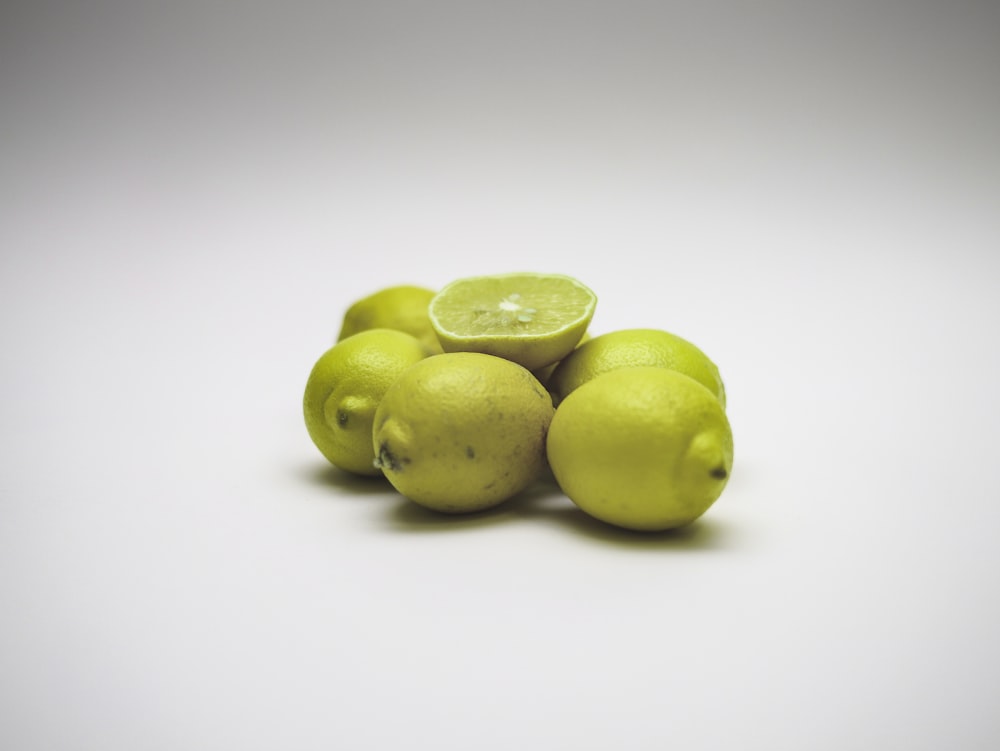 a pile of lemons and a lime on a white background