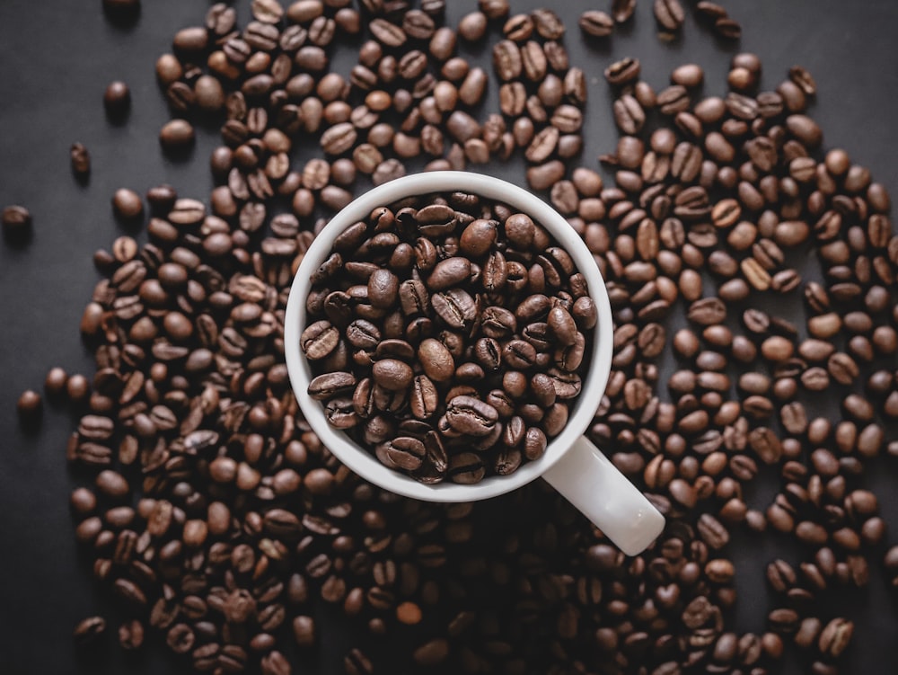 a cup filled with coffee beans on top of a table