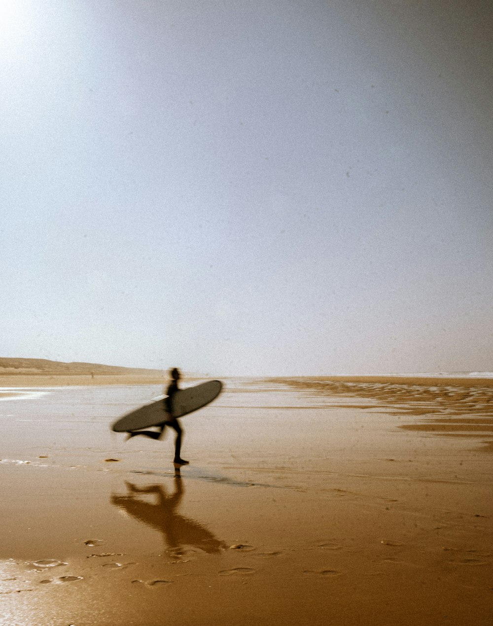 Una persona con una tavola da surf che cammina su una spiaggia