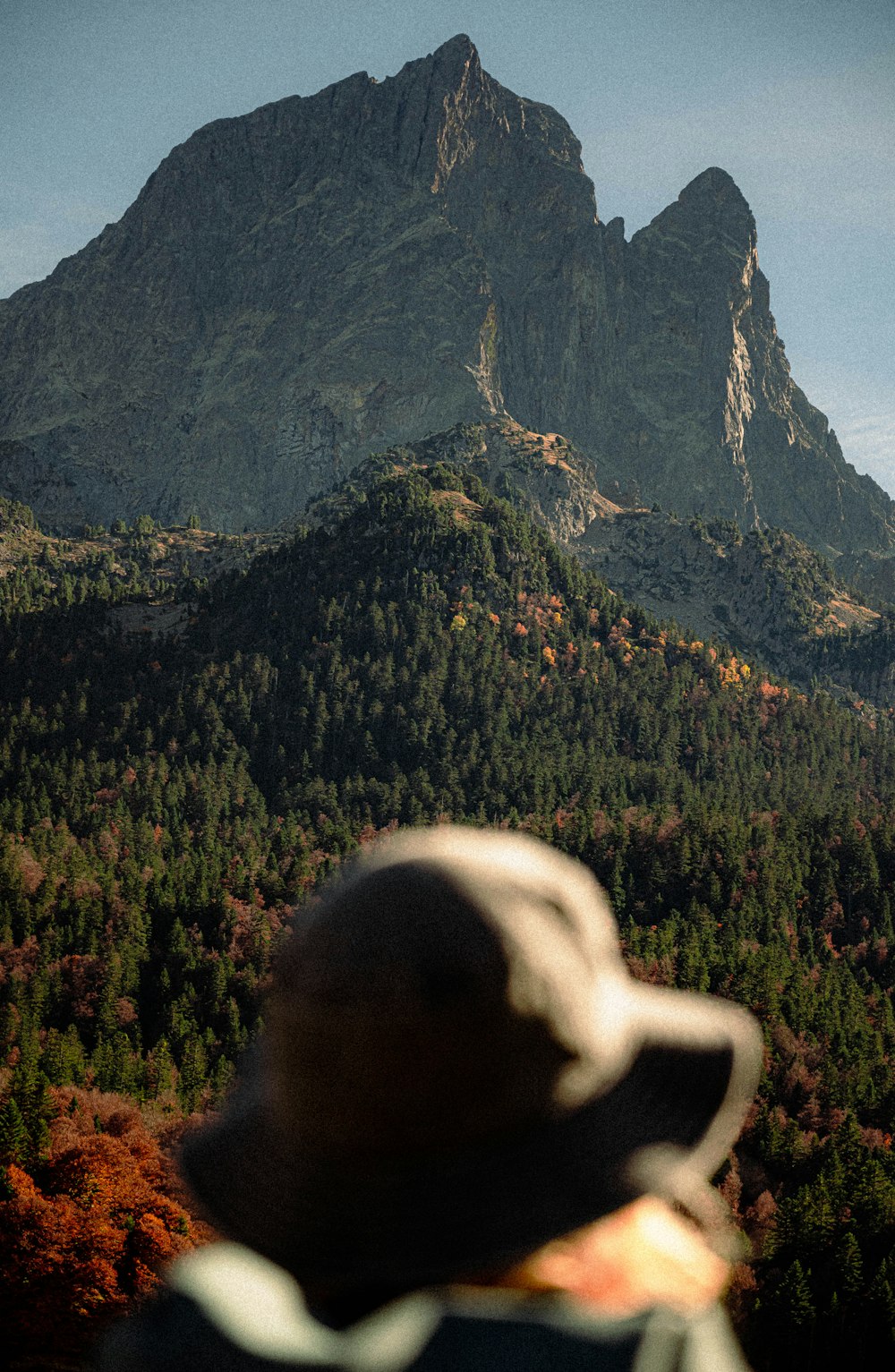 a person with a hat looking at a mountain