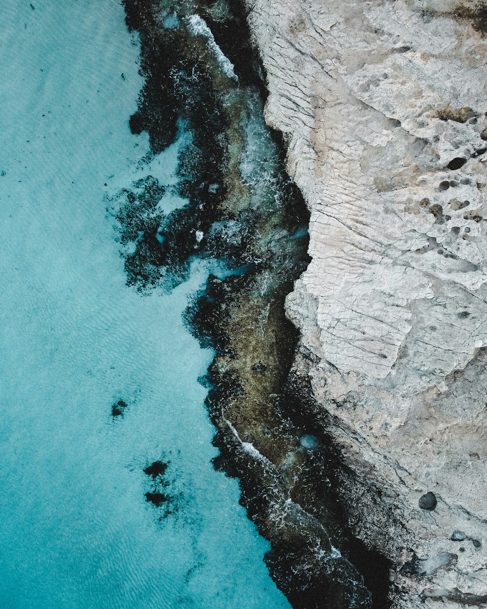 an aerial view of a body of water near a cliff