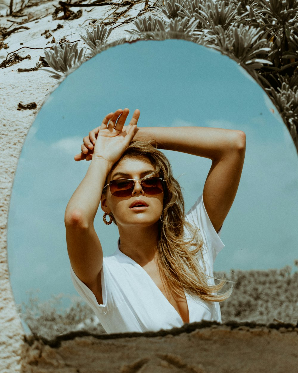 a woman wearing sunglasses is standing in front of a mirror