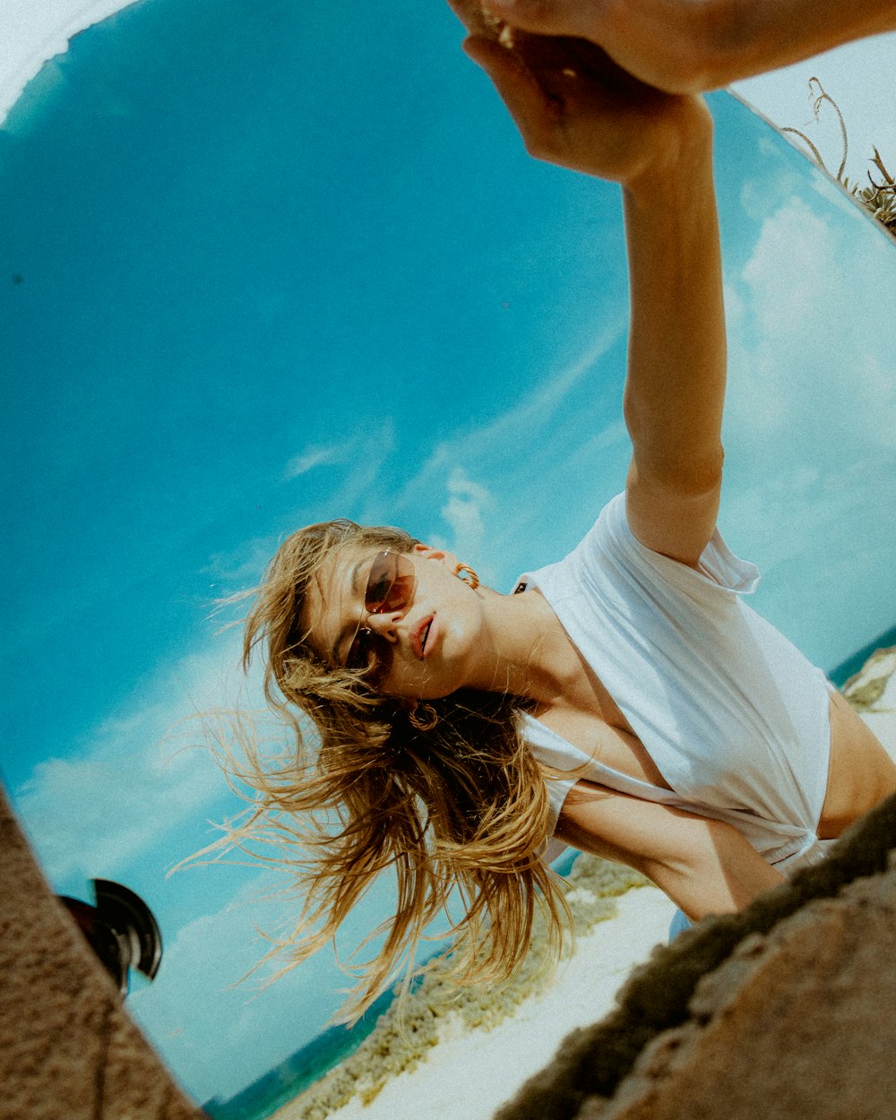 a woman in a white shirt is holding a cell phone