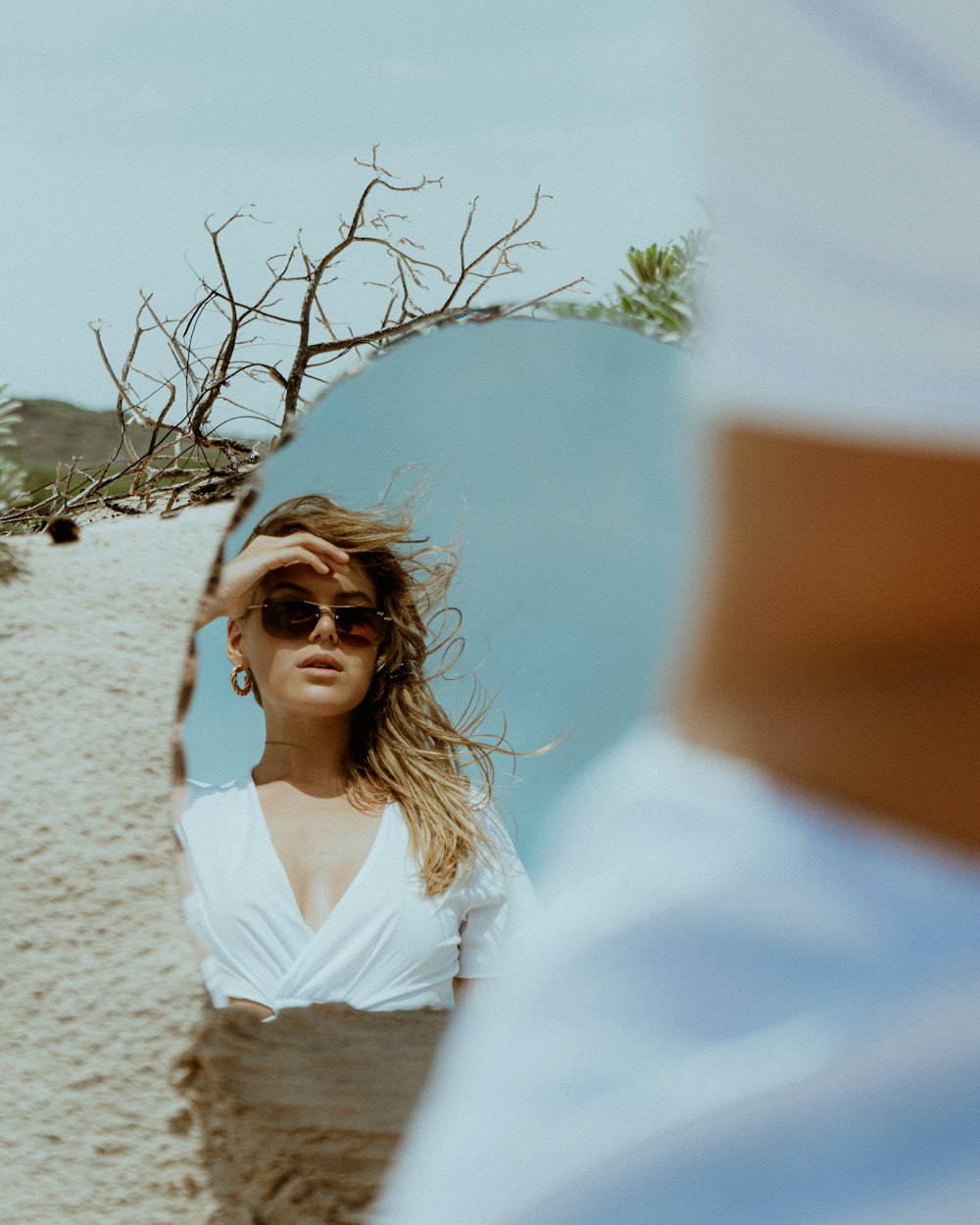 a woman in a white top is looking at herself in a mirror