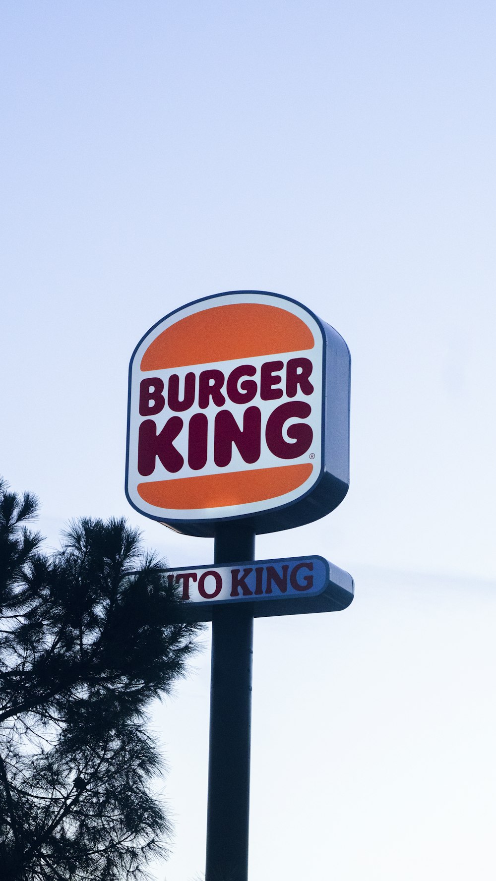 Ein Burger-King-Schild mit einem Baum im Hintergrund