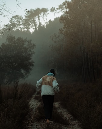 Person wearing a waterproof jacket hiking through a misty forest trail