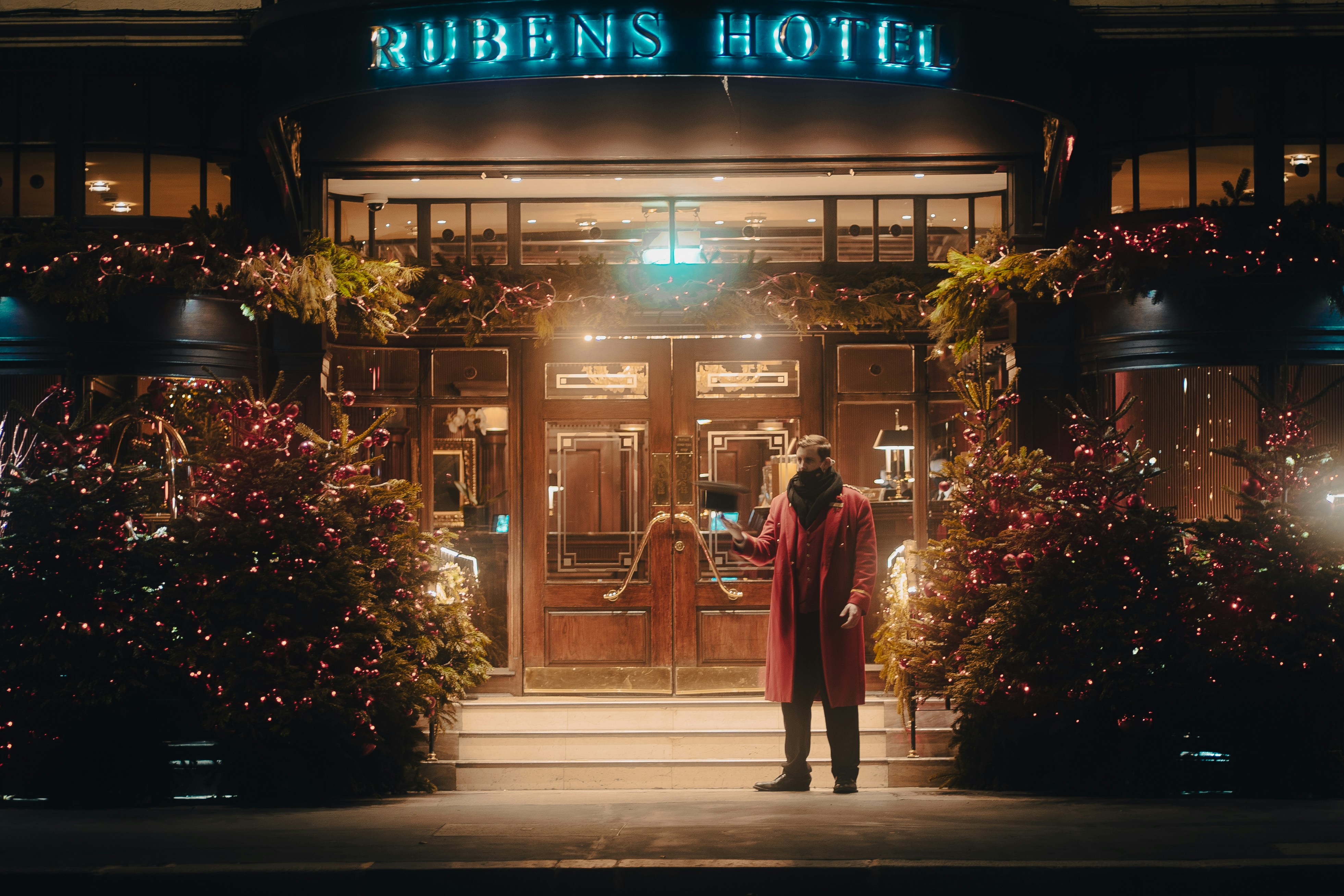 A guest standing outside a warmly lit London boutique hotel entrance at night