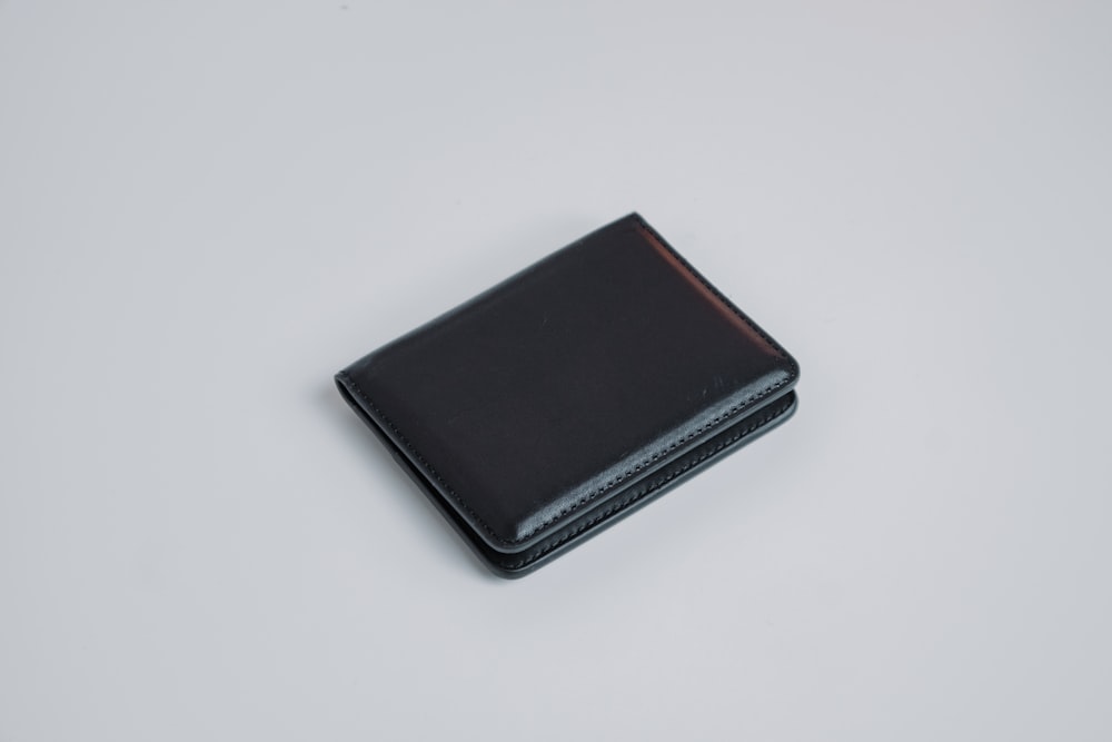 Un portafoglio nero seduto sopra un tavolo bianco