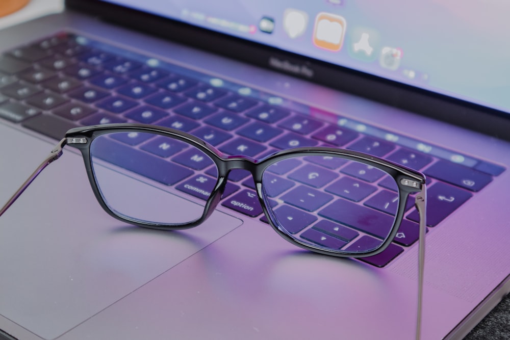 a pair of glasses sitting on top of a laptop keyboard
