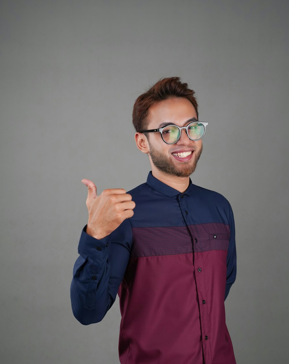 a man wearing glasses giving a thumbs up