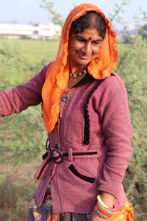 Woman wearing a bold orange and purple snood outdoors with autumn leaves in the background