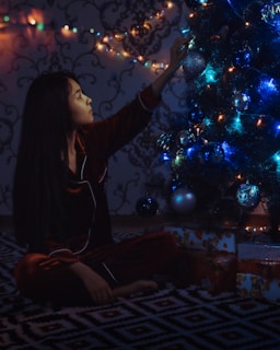 a woman sitting in front of a christmas tree