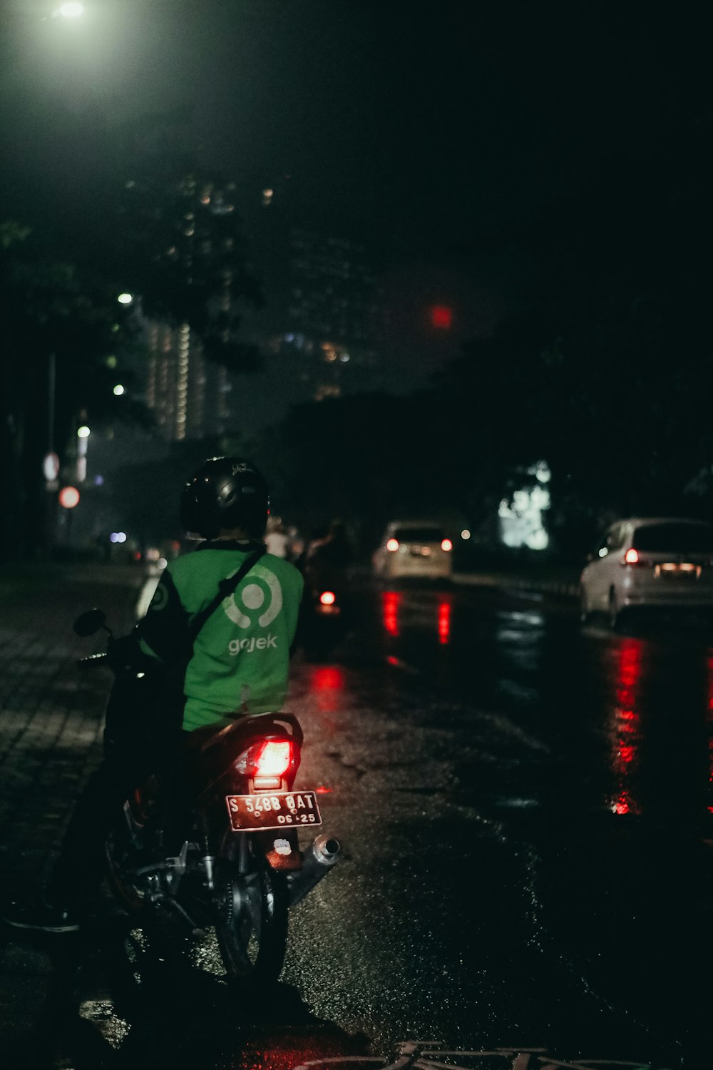 um homem andando de moto por uma rua à noite