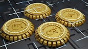 Four golden coins with different cryptocurrency logos are positioned in a grid-like arrangement on a dark, futuristic surface with intersecting white lines.