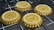 Four golden coins with different cryptocurrency logos are positioned in a grid-like arrangement on a dark, futuristic surface with intersecting white lines.