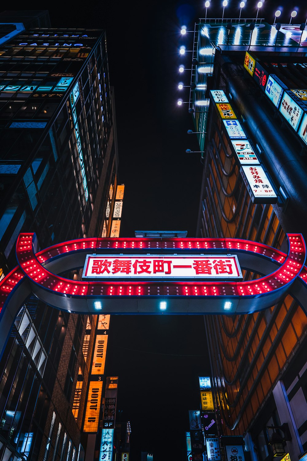 a city street at night with a neon sign in the middle of the street
