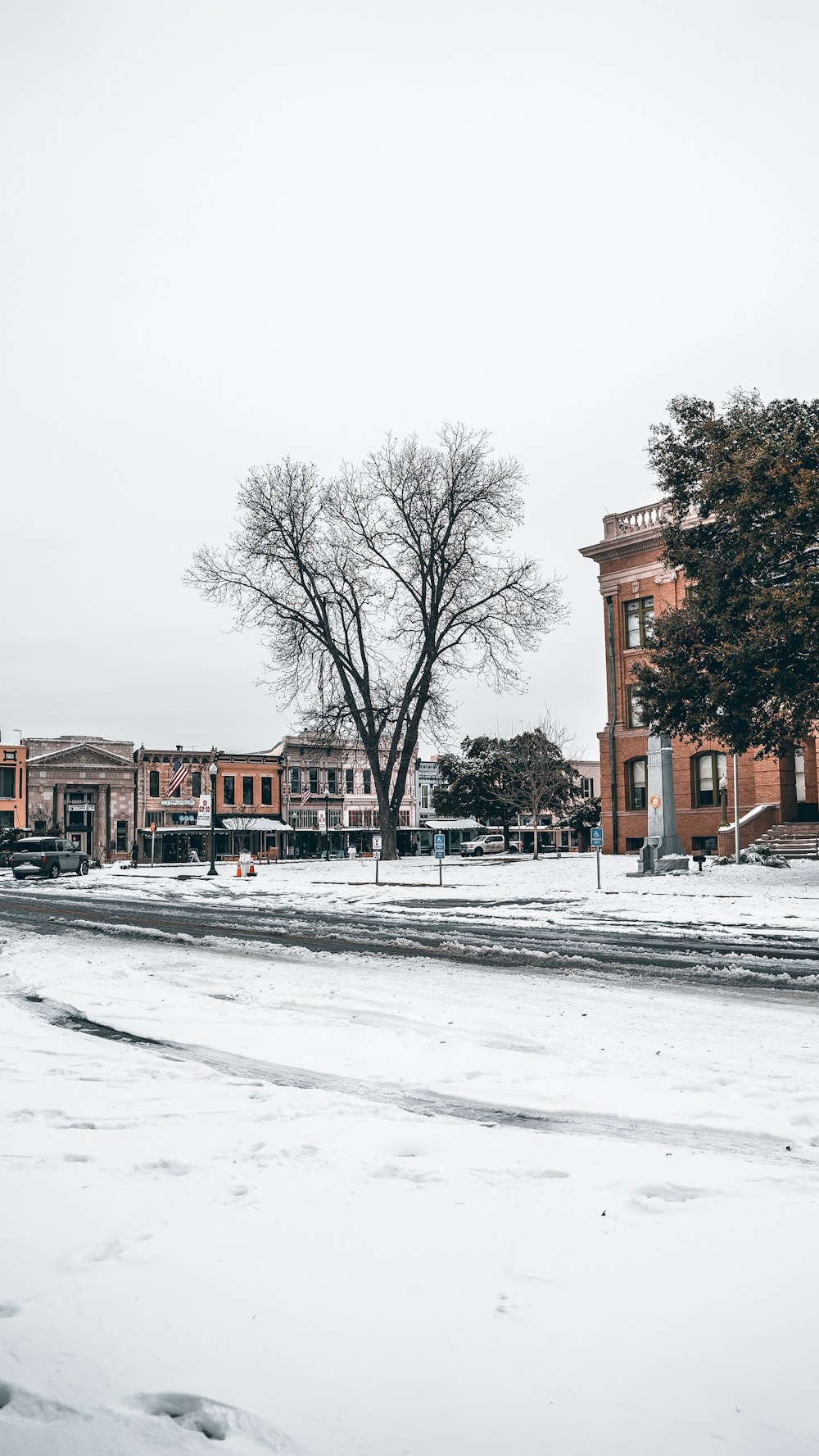 a snow covered street with buildings in the background