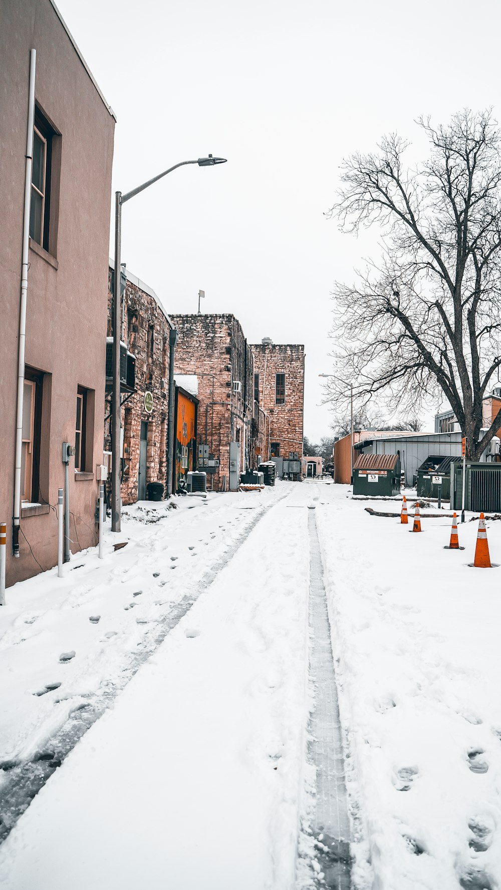 a snow covered street with orange traffic cones