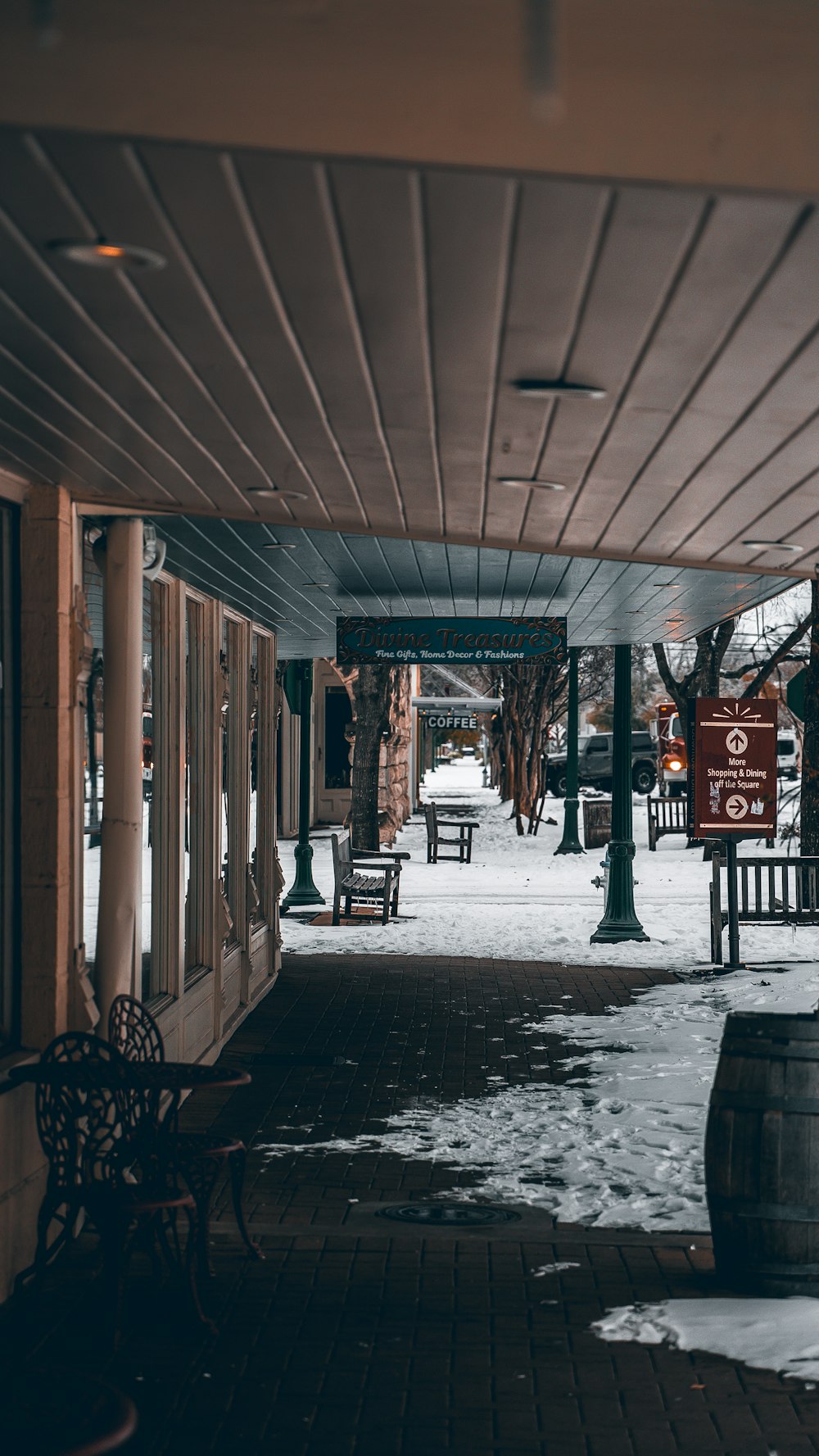 a snowy sidewalk with benches and a sign