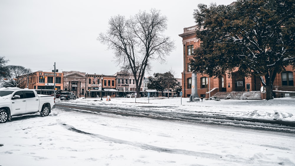 a white truck driving down a snow covered street