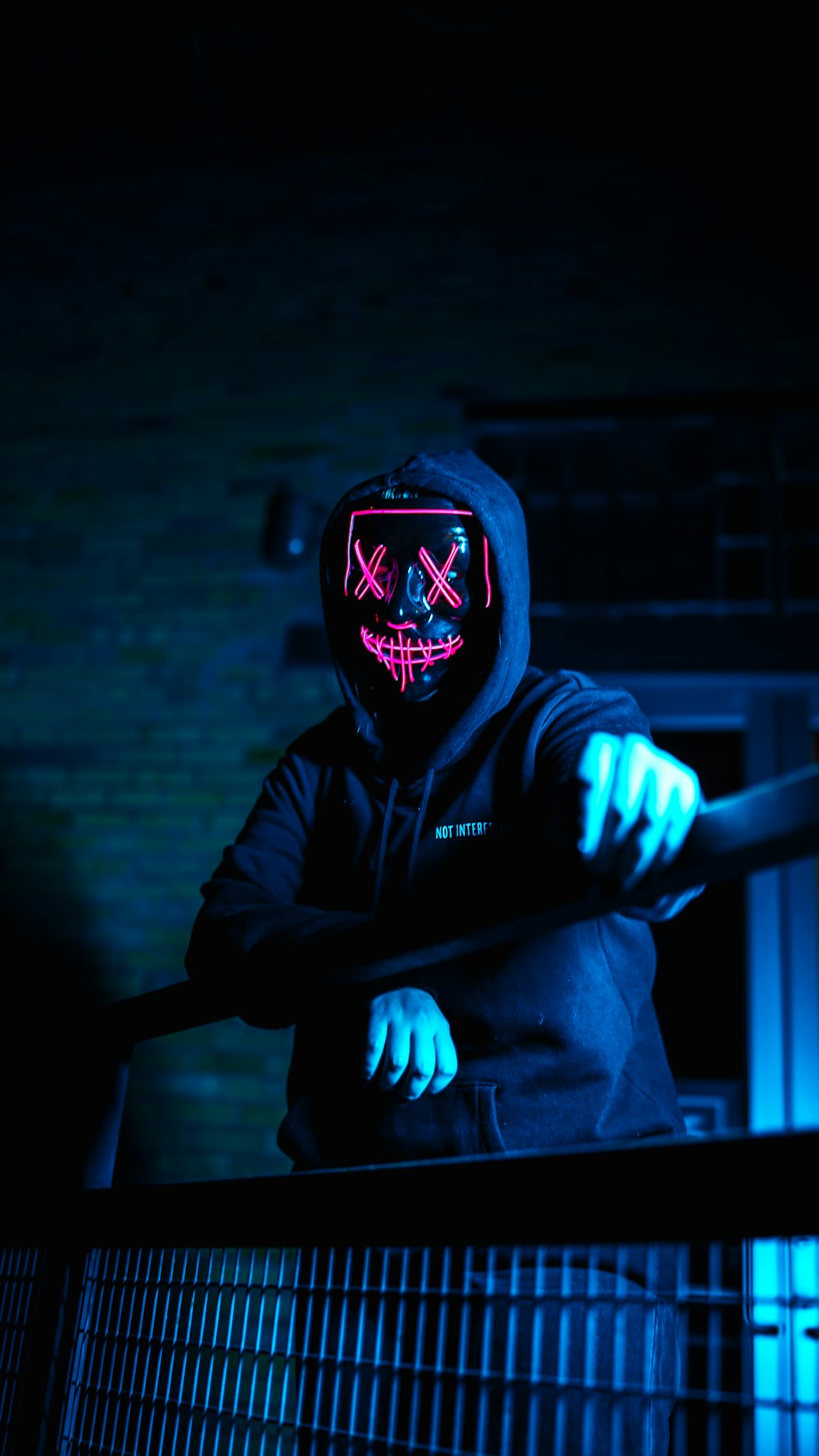 a person wearing a neon mask standing in the dark