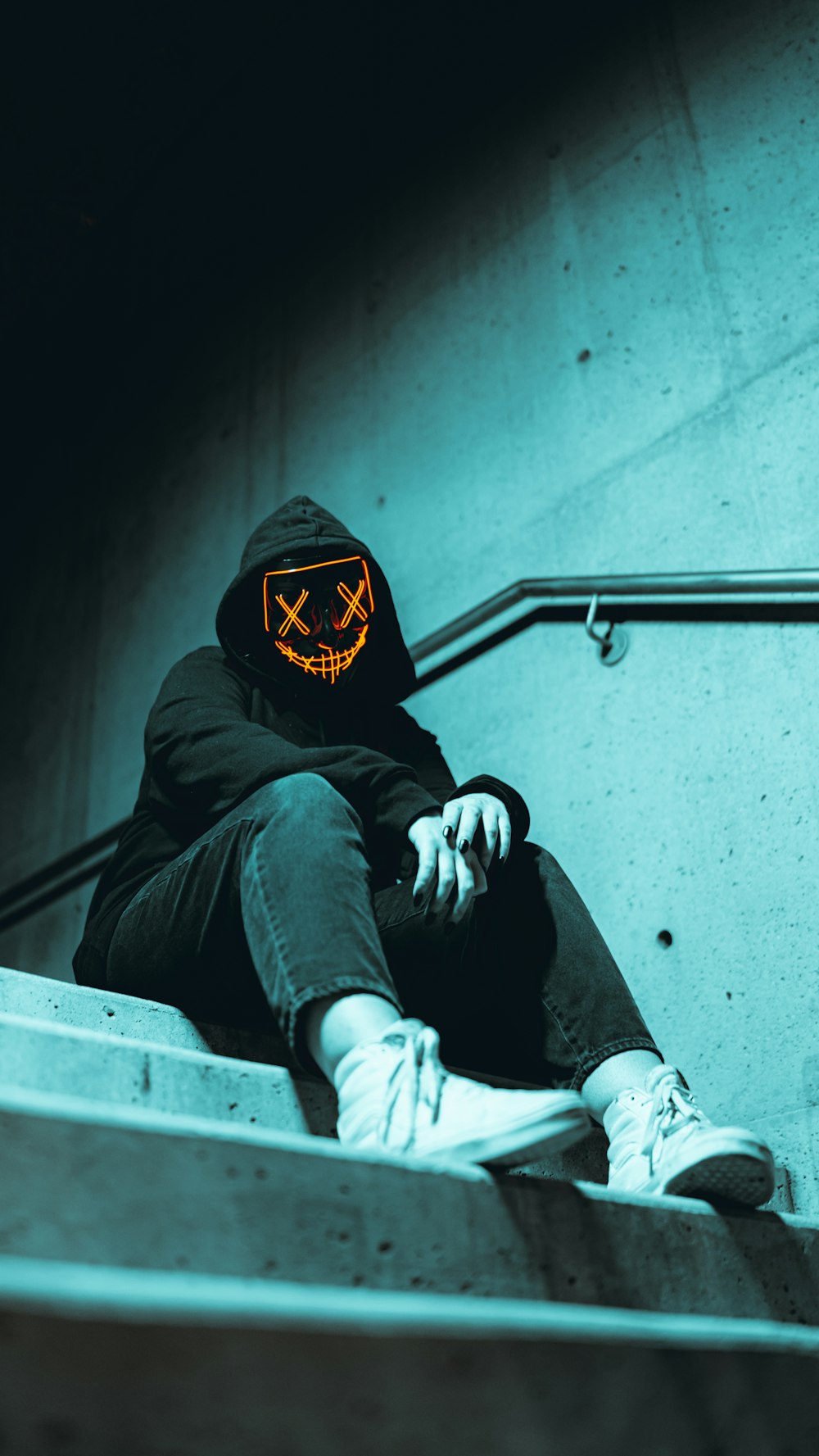 a person wearing a hoodie sitting on a set of stairs