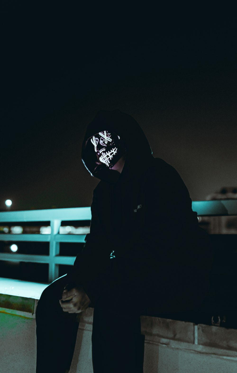 a man in a hoodie sitting on a ledge