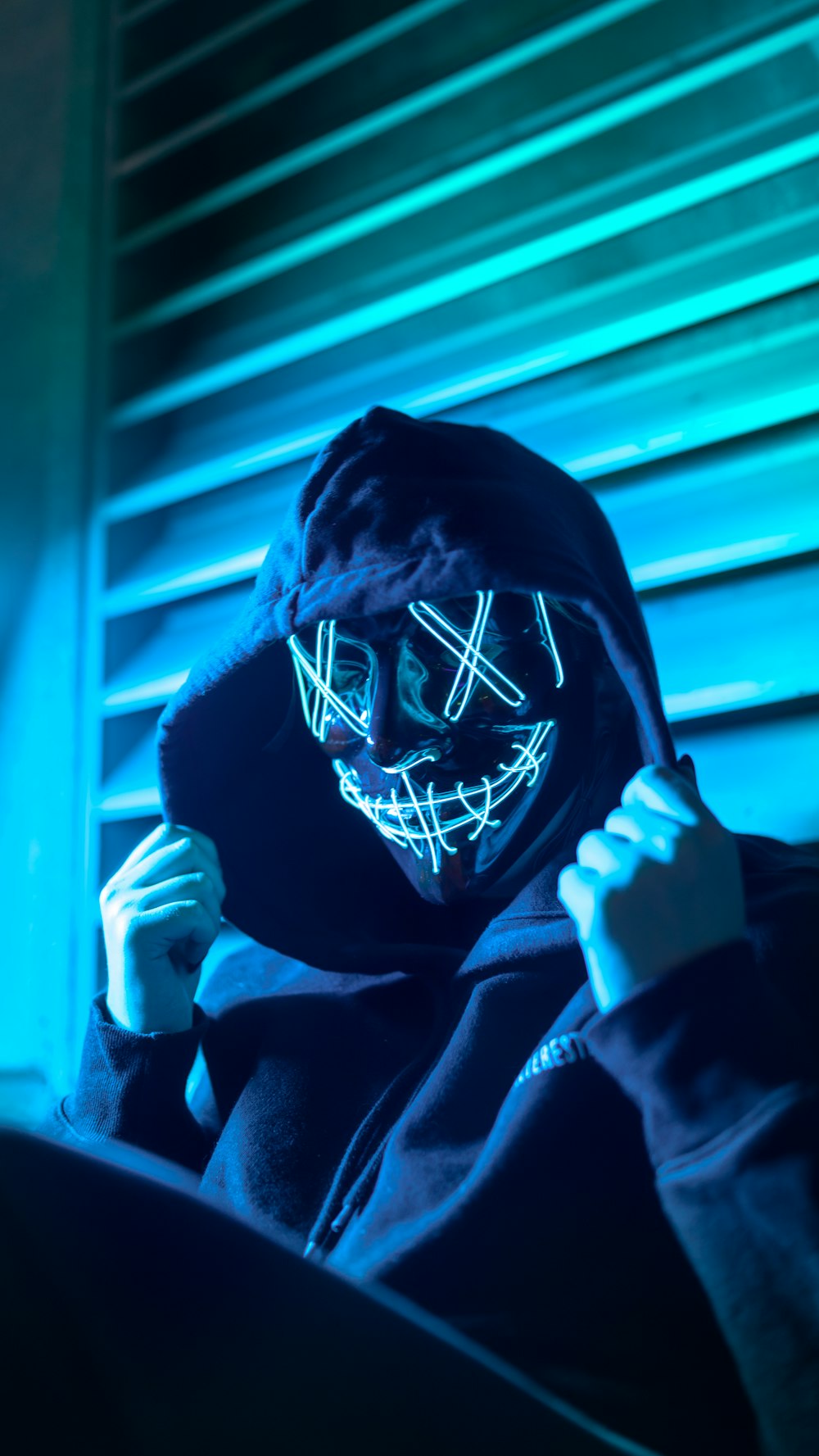 a person wearing a neon mask in a dark room