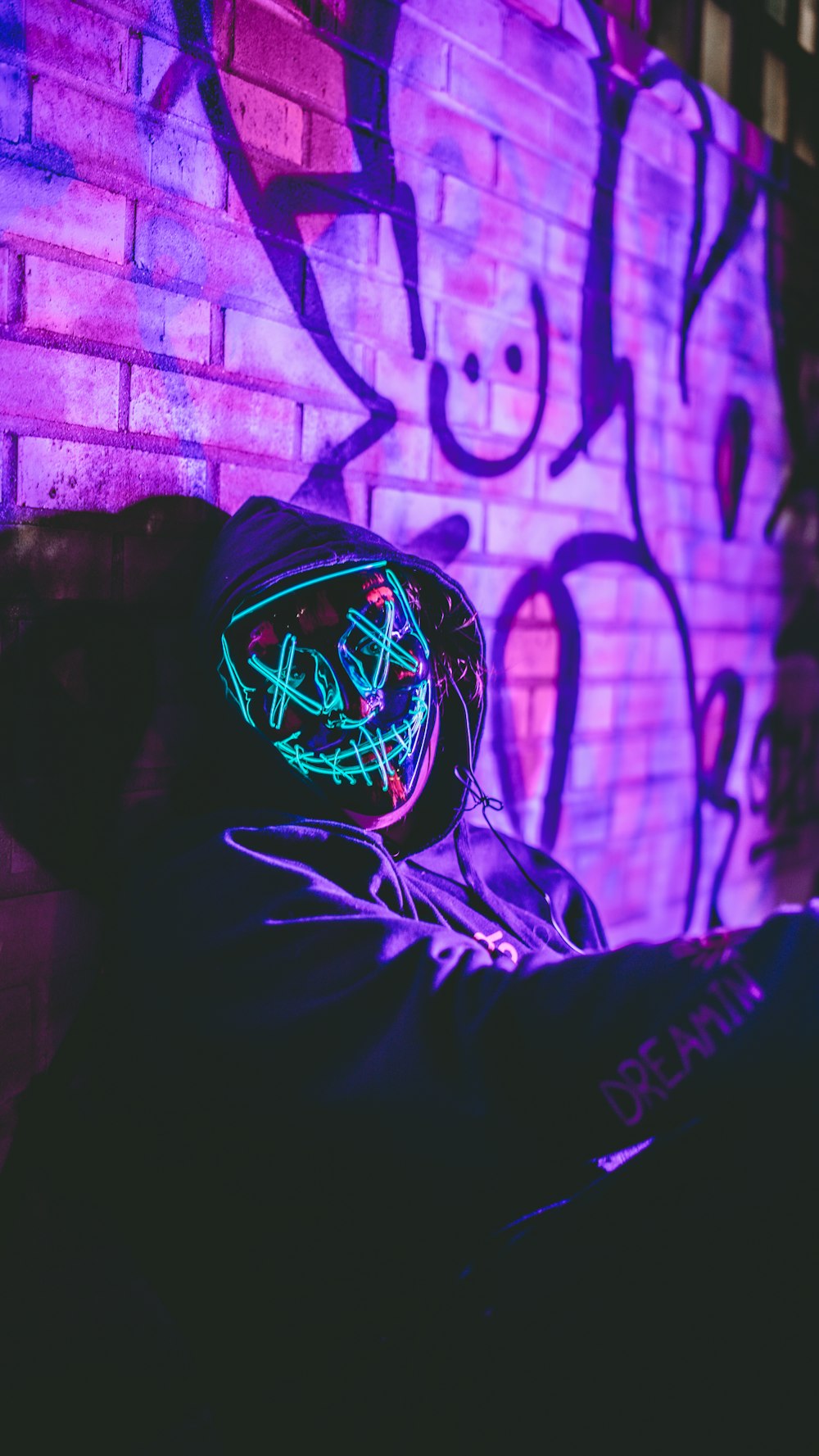 a person sitting in front of a brick wall with graffiti on it