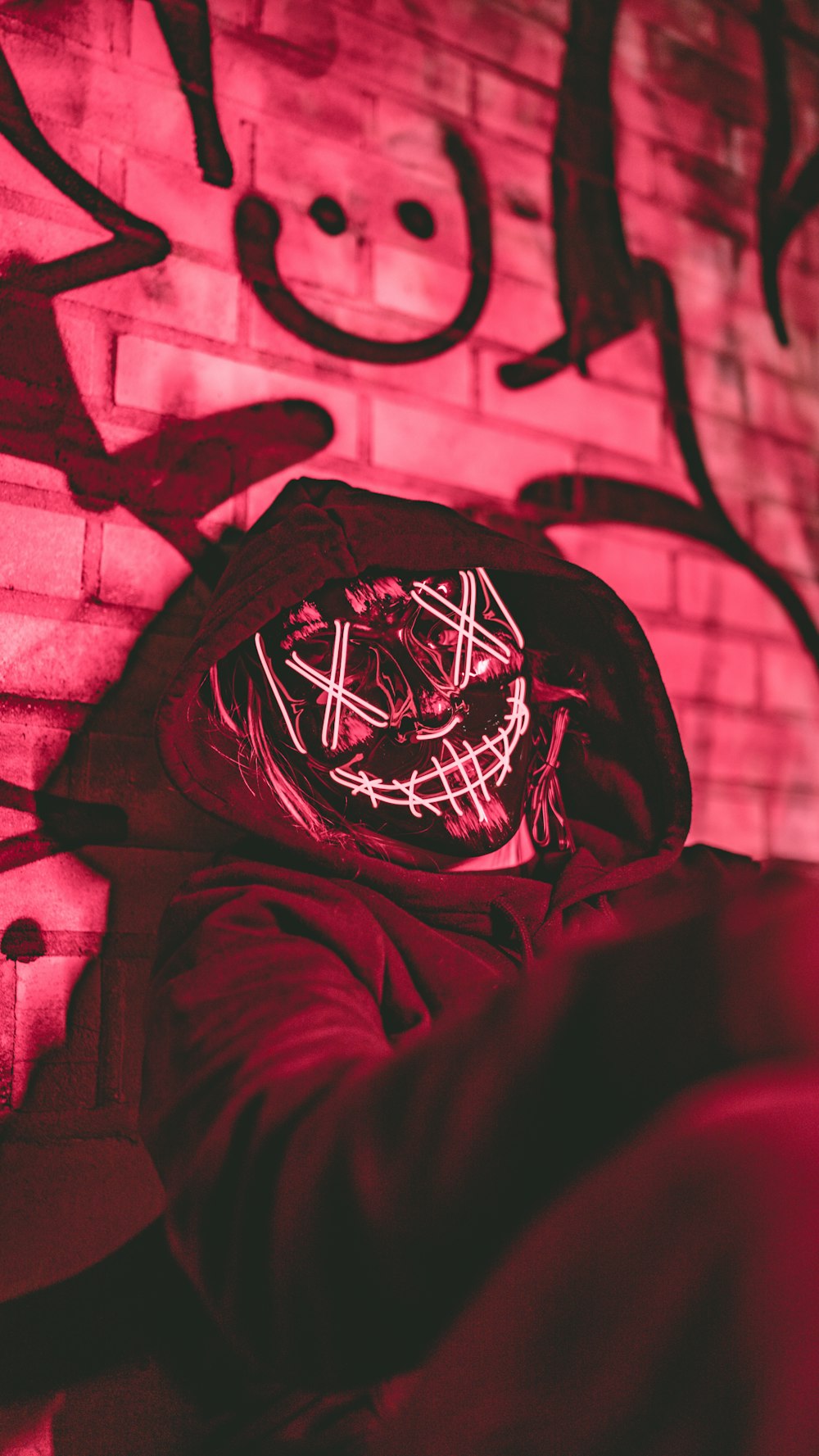 a person wearing a mask in front of a brick wall