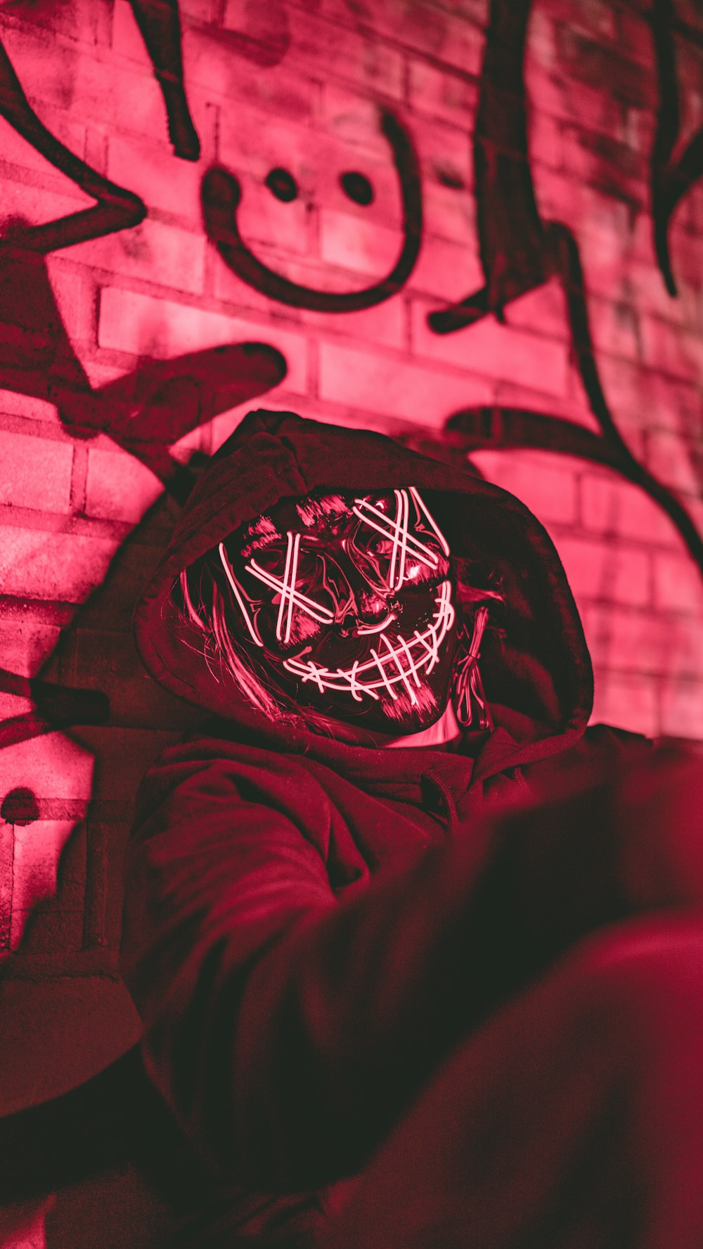 Una persona con una máscara frente a una pared de ladrillos