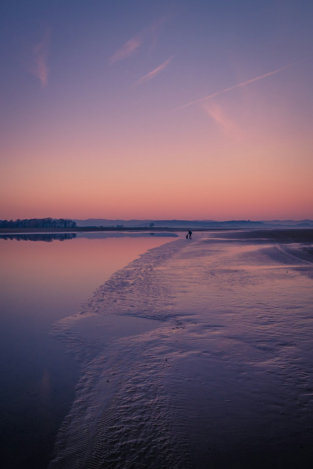 a person walking on a beach at sunset